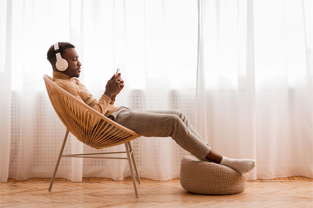 Relaxed Man In Wireless Headset Using Mobile Phone Listening To Audiobook