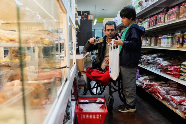 Abdul Salam, center, and his son Ahmad Sodais shop for sweet treats inside of an Afghan grocery store in Carmichael, Calif., Friday, Dec. 5, 2025. (AP Photo/Godofredo A. Vásquez)