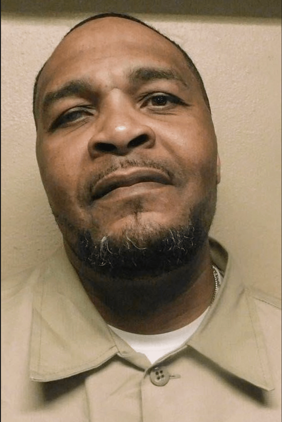 A close-up portrait of a middle-aged Black man with a beard, looking directly at the camera with a serious expression.