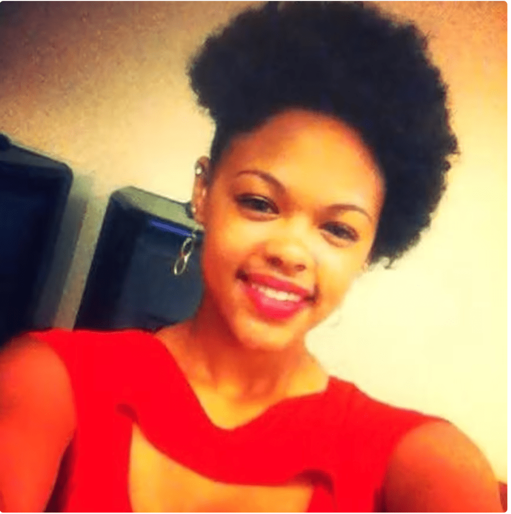A smiling woman with curly black hair wearing a red top.