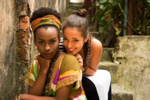 Two Young Diverse Cuban Women in Their 20s Smiling Together on Outdoor Steps
