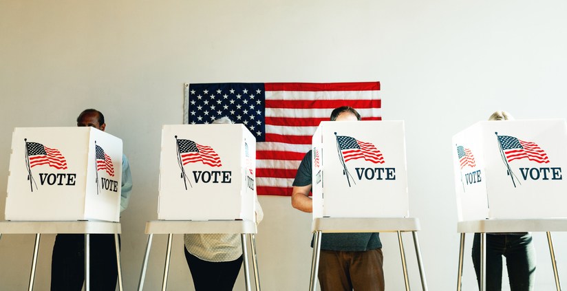 Diverse voters, including men and women, casting ballots in an election booth.