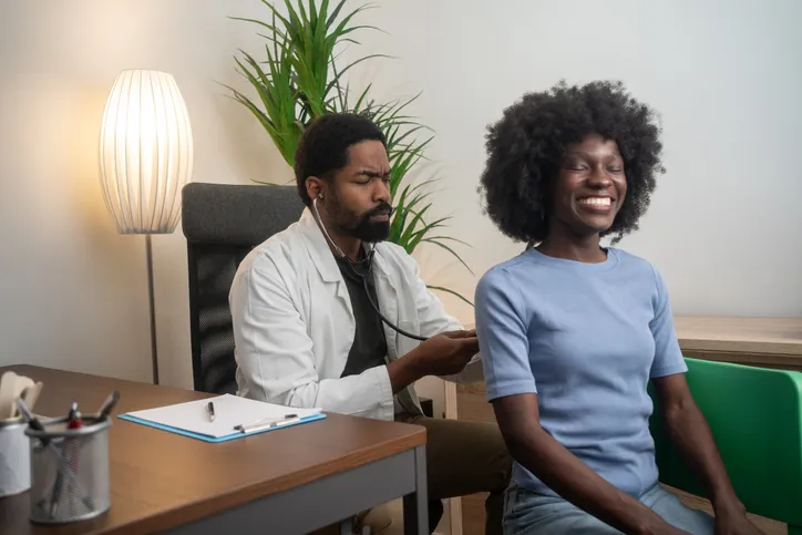 Black Male Doctor Examining Patient in Clinic