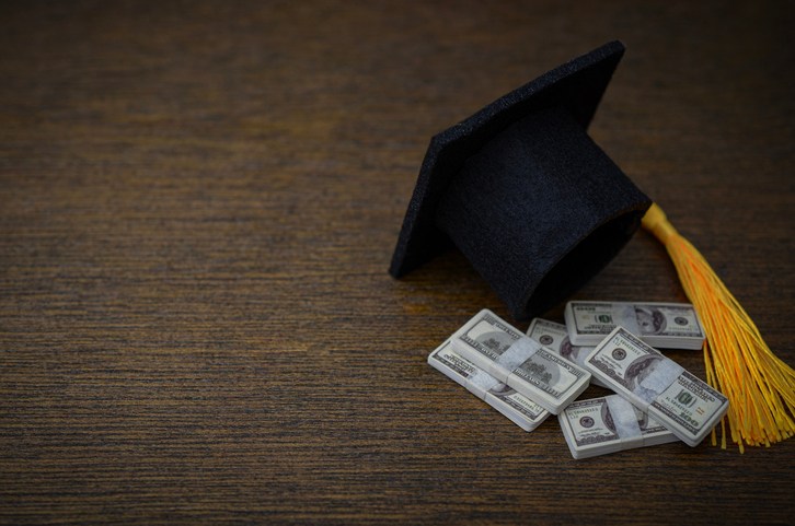 Graduation Cap with Cash Bundles Representing Student Debt, Tuition Fees and Higher Education Costs