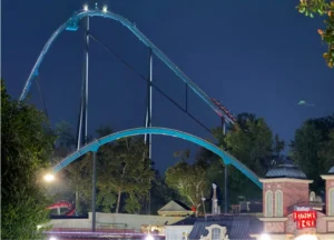 Goliath roller coaster illuminated at night at Six Flags Over Georgia, with a red train descending the steep track, surrounded by trees and park buildings with "FRIGHT FEST" signage visible.